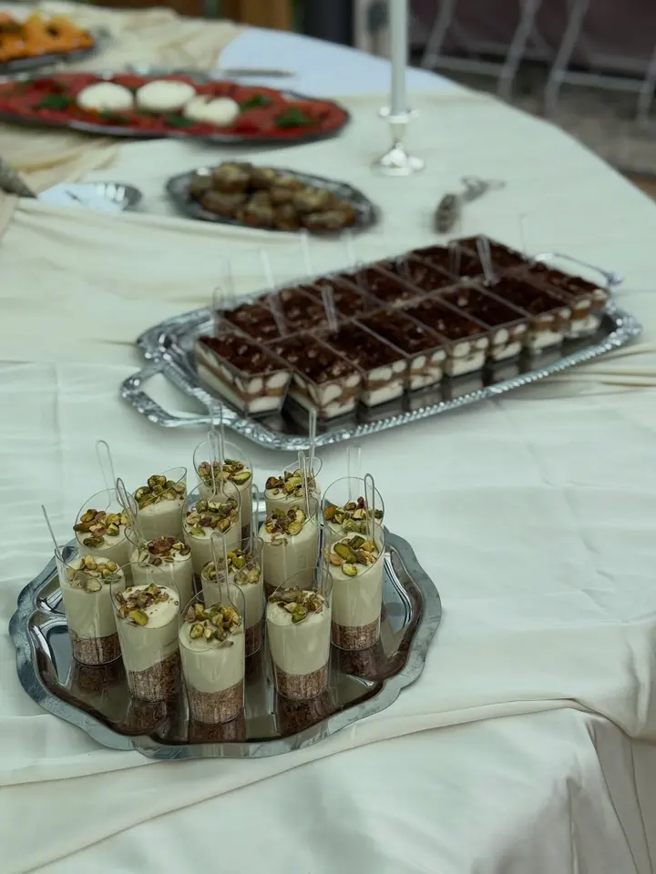 Desserttafel voor een babyshower met tiramisucups en chocoladetaart op zilveren schalen
