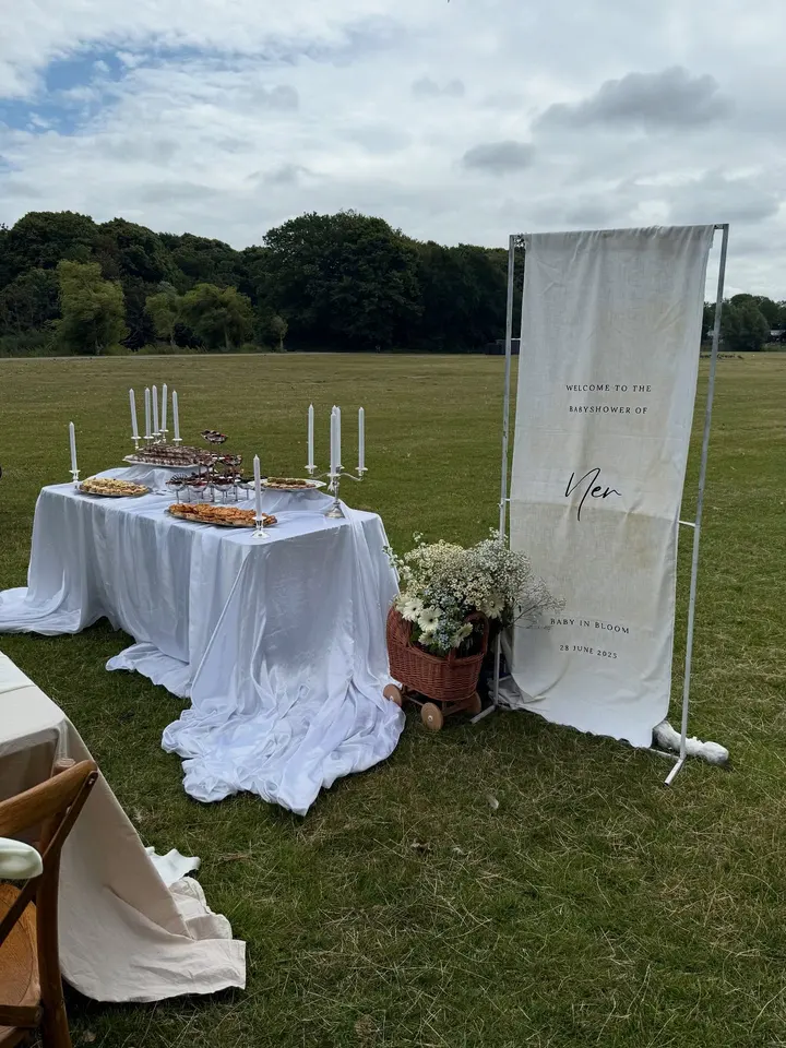Brunchbuffet op een witte tafel in het groen, klaar voor een babyshower