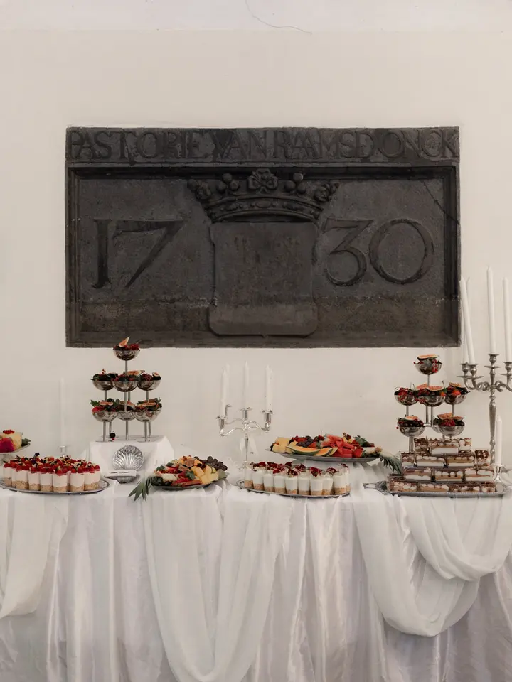 Lange witte fruit- en desserttafel met etagères in een historische zaal