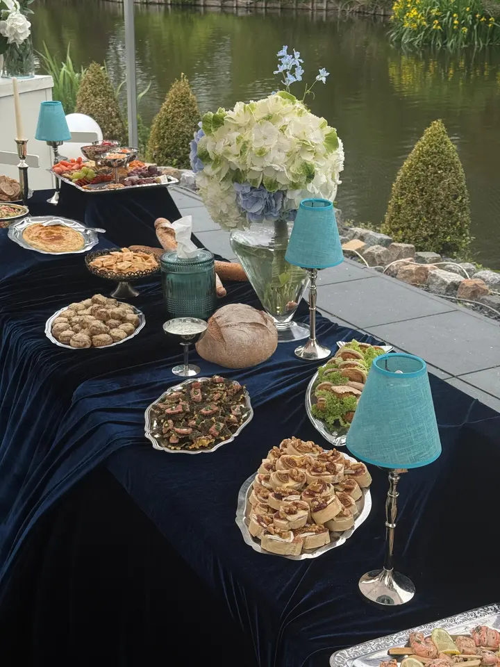 Lunchtafel in vintage blauw met bloemen en hapjes aan het water